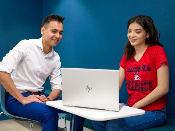 A male and female sitting at a table with a laptop